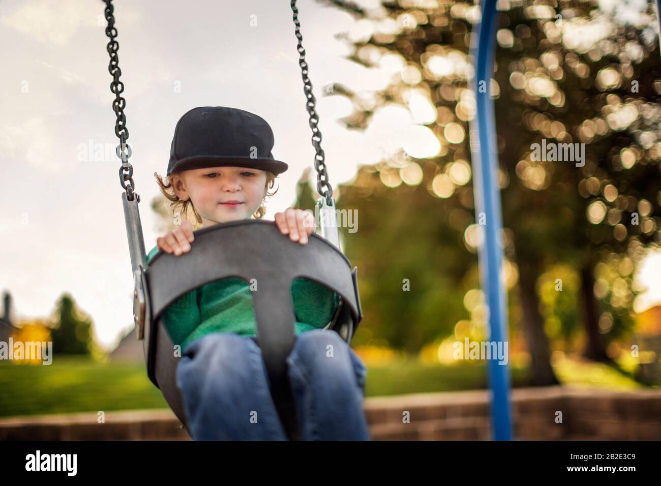 Ragazzo giovane che gioca a swing in un parco giochi Foto Stock