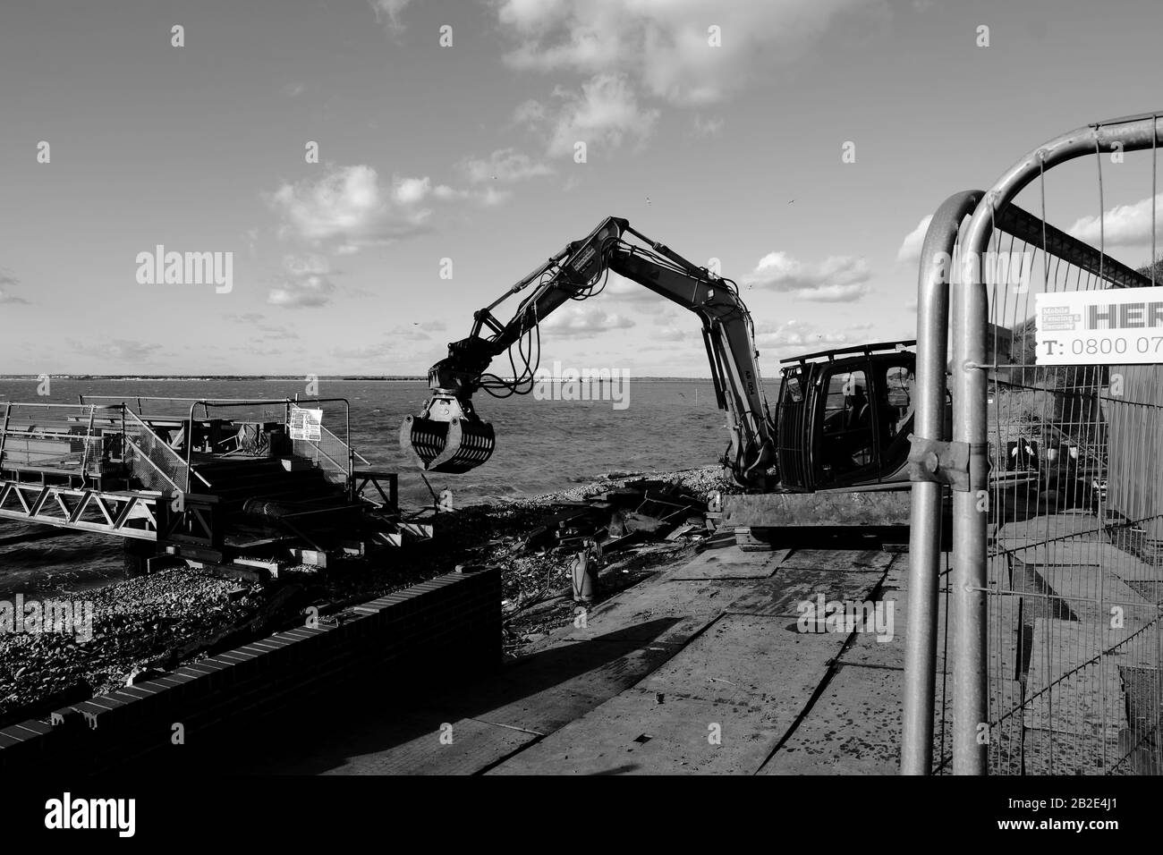 Un Kobelco Crawler svolge un lavoro di demolizione, eliminando macerie e rifiuti edili da un sito costiero di Totland Bay sull'isola di Wight Foto Stock