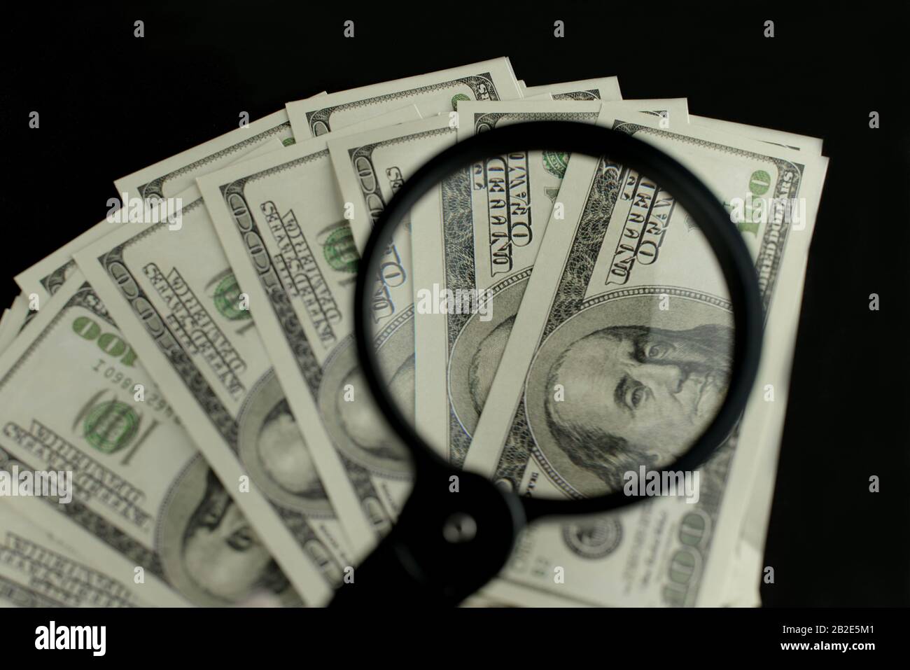 Sfondo di un sacco di banconote di denaro di 100 dollari canadesi americani in un mucchio con una lente d'ingrandimento che aumenta le entrate Foto Stock