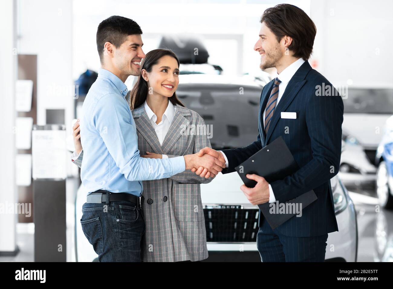 Uomo Che Si Stringe Le Mani Con Il Responsabile Delle Vendite Di Auto Nel Dealership Store Foto Stock
