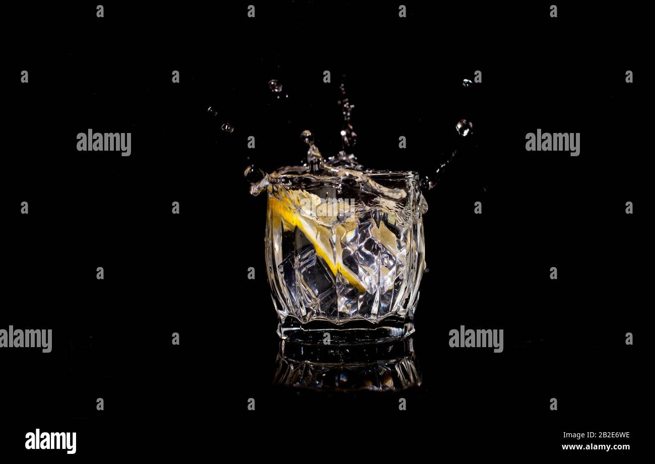 l'acqua aqua con soda di limone si versa quando il ghiaccio è gettato con le gocce su un backgroun nero Foto Stock