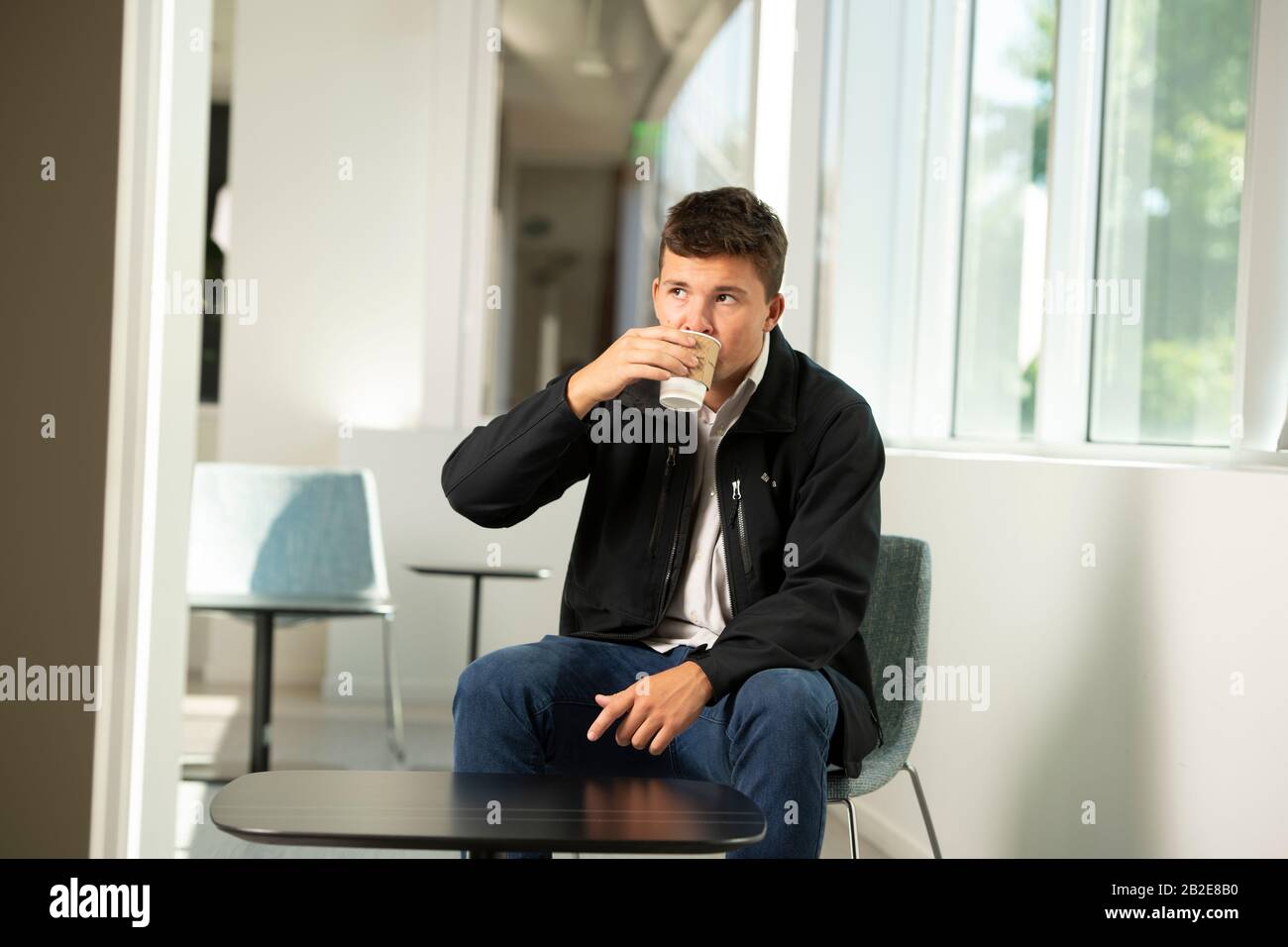 giovane adulto maschio bere caffè in un ambiente moderno business Foto Stock