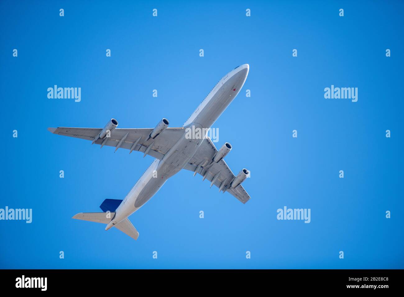 sotto la pancia del passeggero commerciale jet su cielo blu nuvoloso Foto Stock
