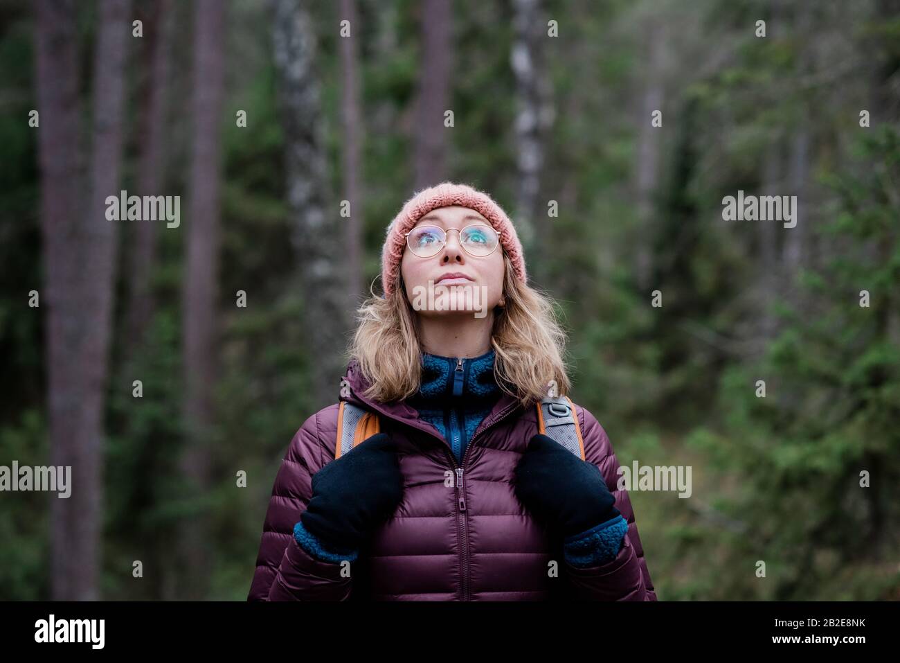 ritratto di una donna che guarda il cielo in una foresta in inverno Foto Stock