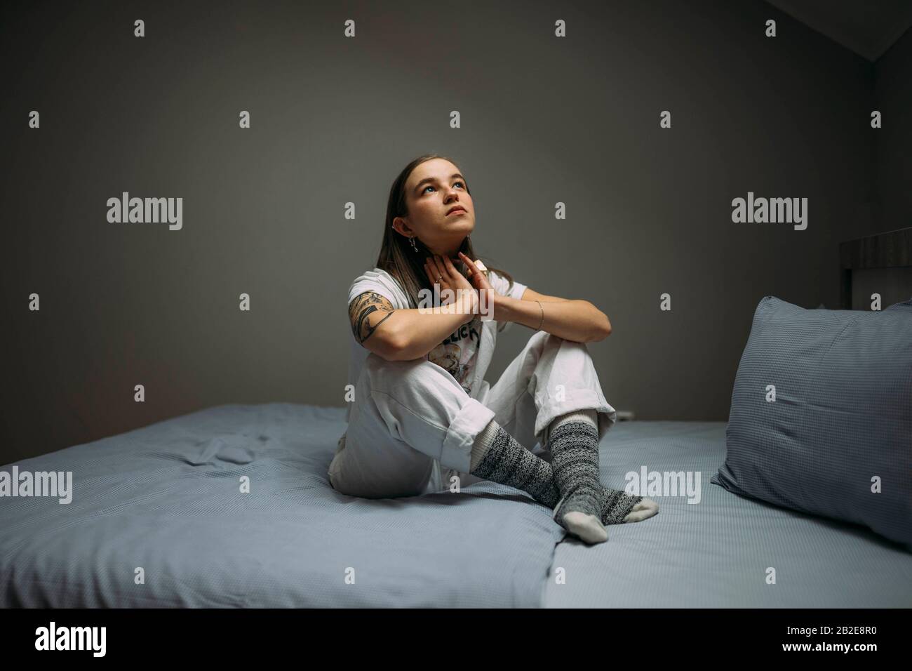 Bella giovane donna tatuata seduta sul letto Foto Stock
