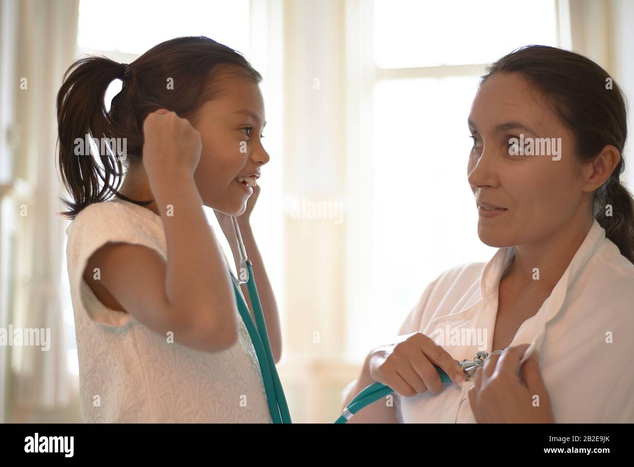 Professionista generale che usa uno stetoscopio durante il check-up una ragazza giovane Foto Stock