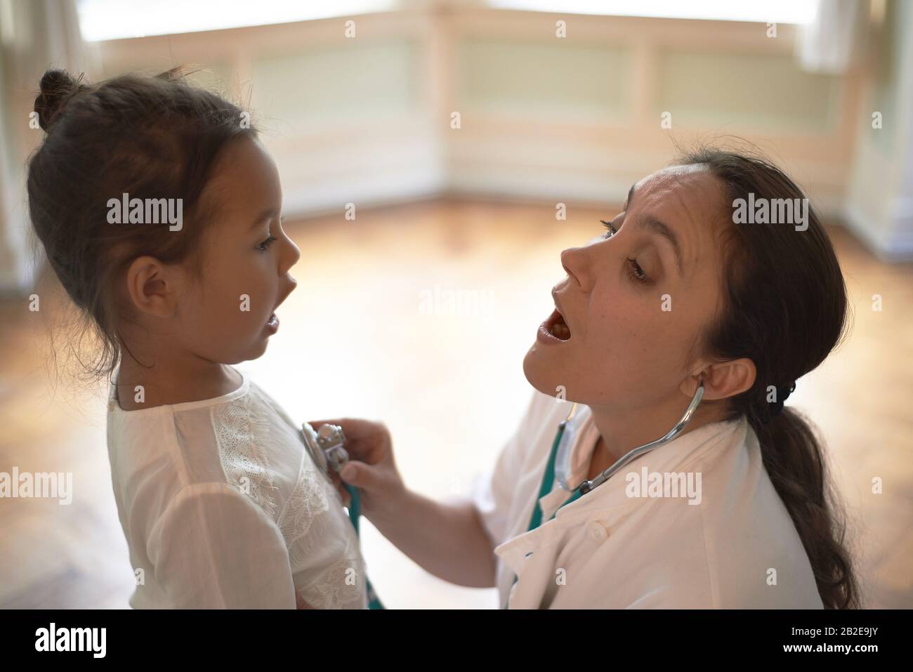 Professionista generale che usa uno stetoscopio durante il check-up una ragazza giovane Foto Stock