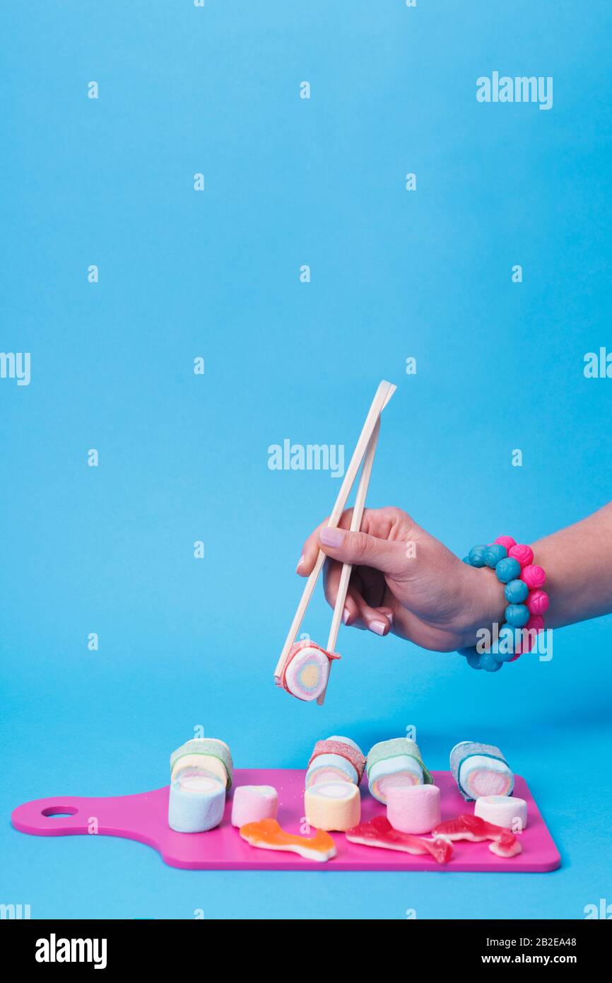 Mano femminile con bacchette con sushi caramella Foto Stock