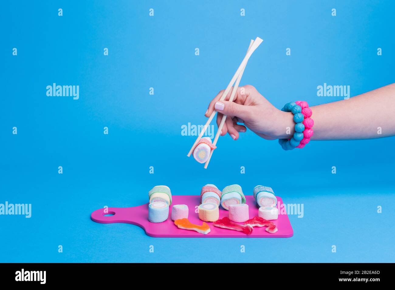 Mano femminile con bacchette con sushi caramella Foto Stock