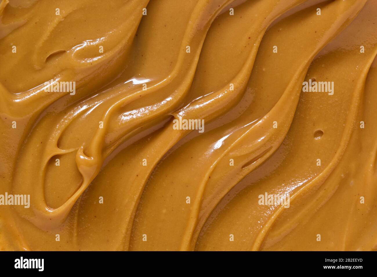 Burro di arachidi texture sfondo. Pasta di noce marrone spalmare la pasta. Deliziosa cucina naturale cremosa diffusione macro vista dall'alto Foto Stock