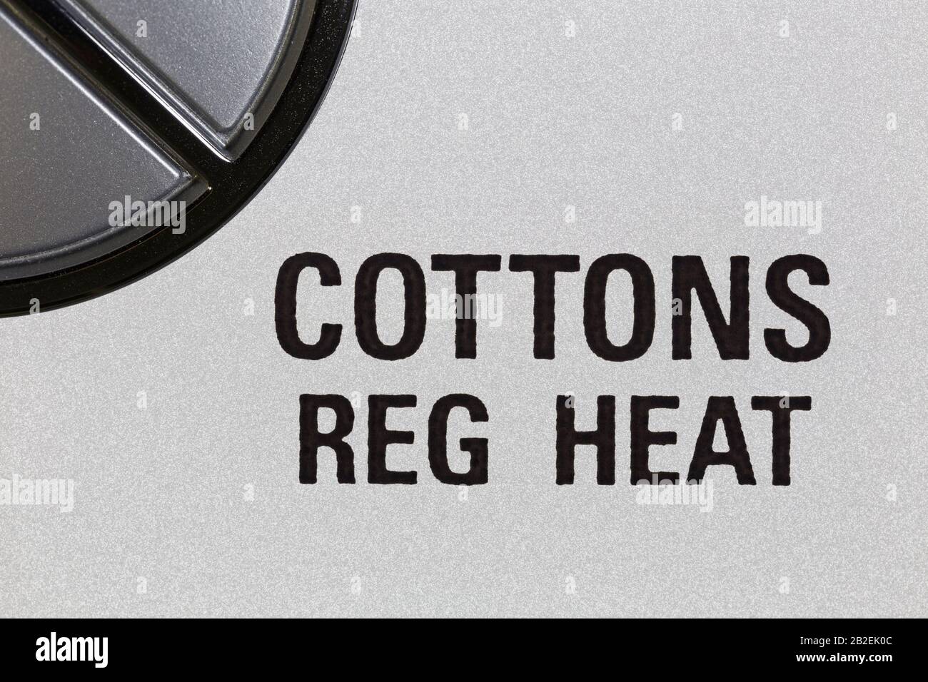 Macro fotografia di cotoni impostazione regolare del calore sulla manopola di controllo dell'essiccatore dell'abbigliamento. Foto Stock