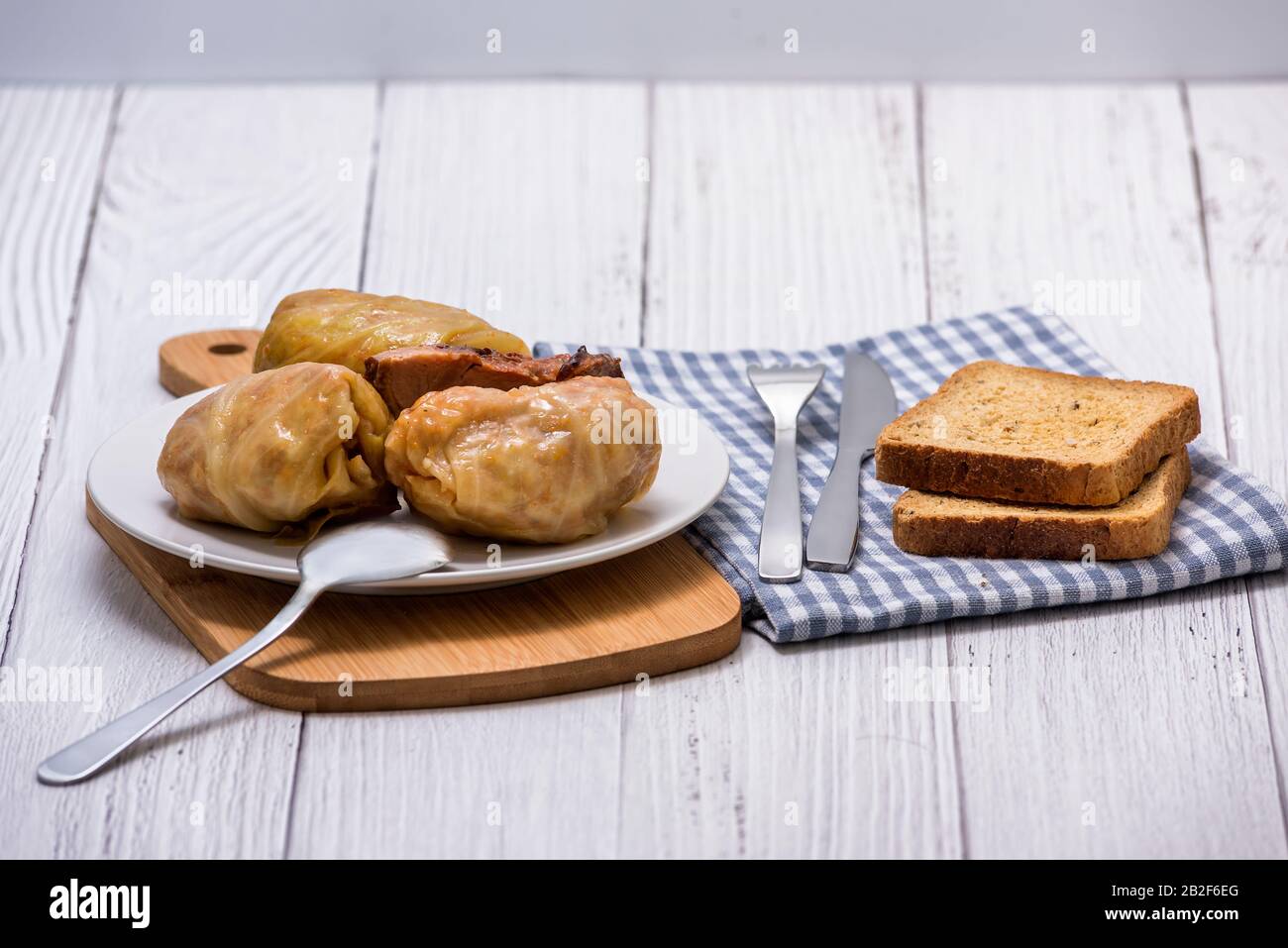 Involtini di cavolo con carne, riso e verdure in un piatto bianco su un tavolo di legno. Foglie di cavolo farcite con carne. Sarma, dolma, Chou farci, golubtsy Foto Stock