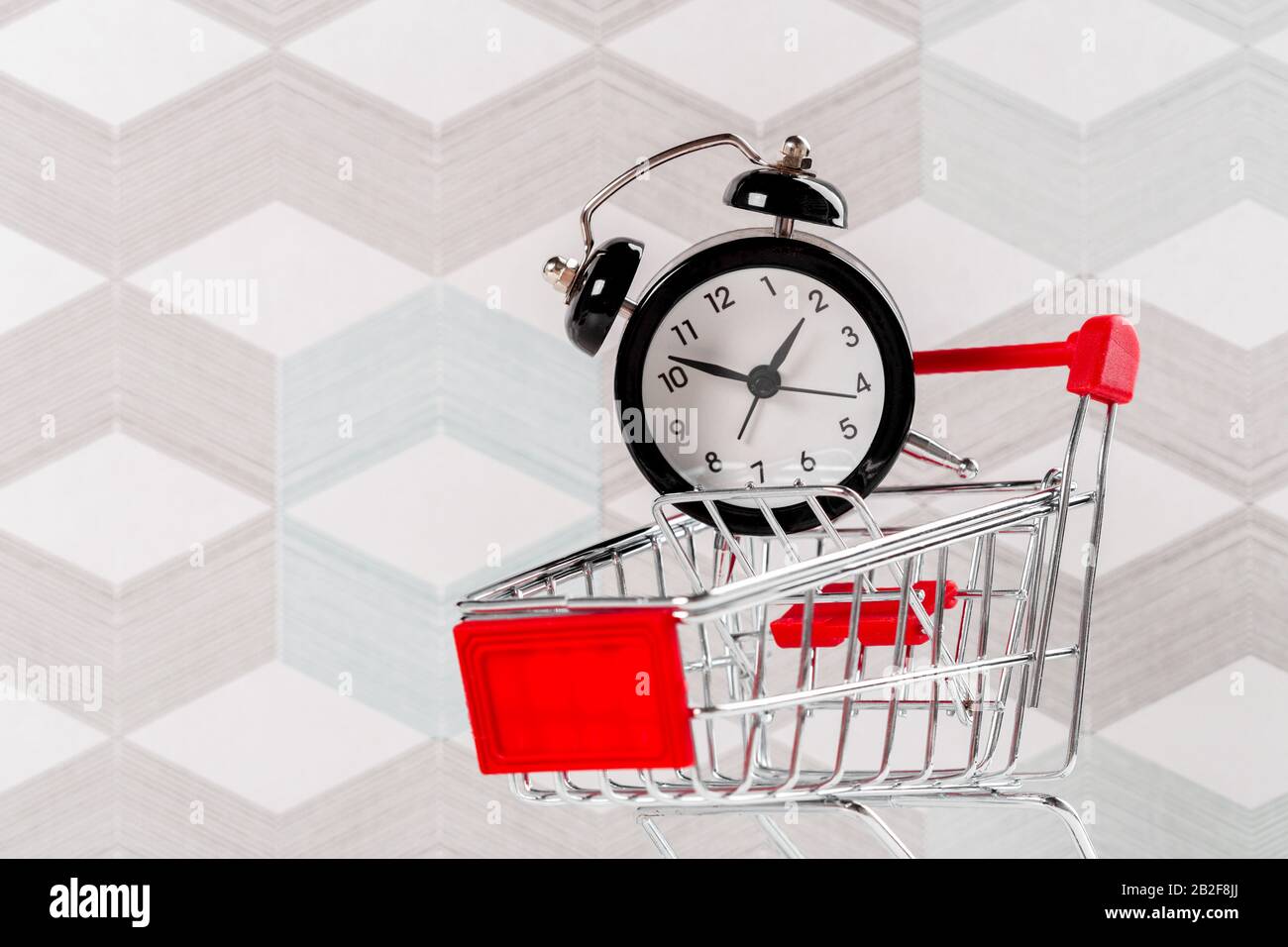 Piccolo carrello con sveglia. Concetto di tempo di shopping Foto Stock