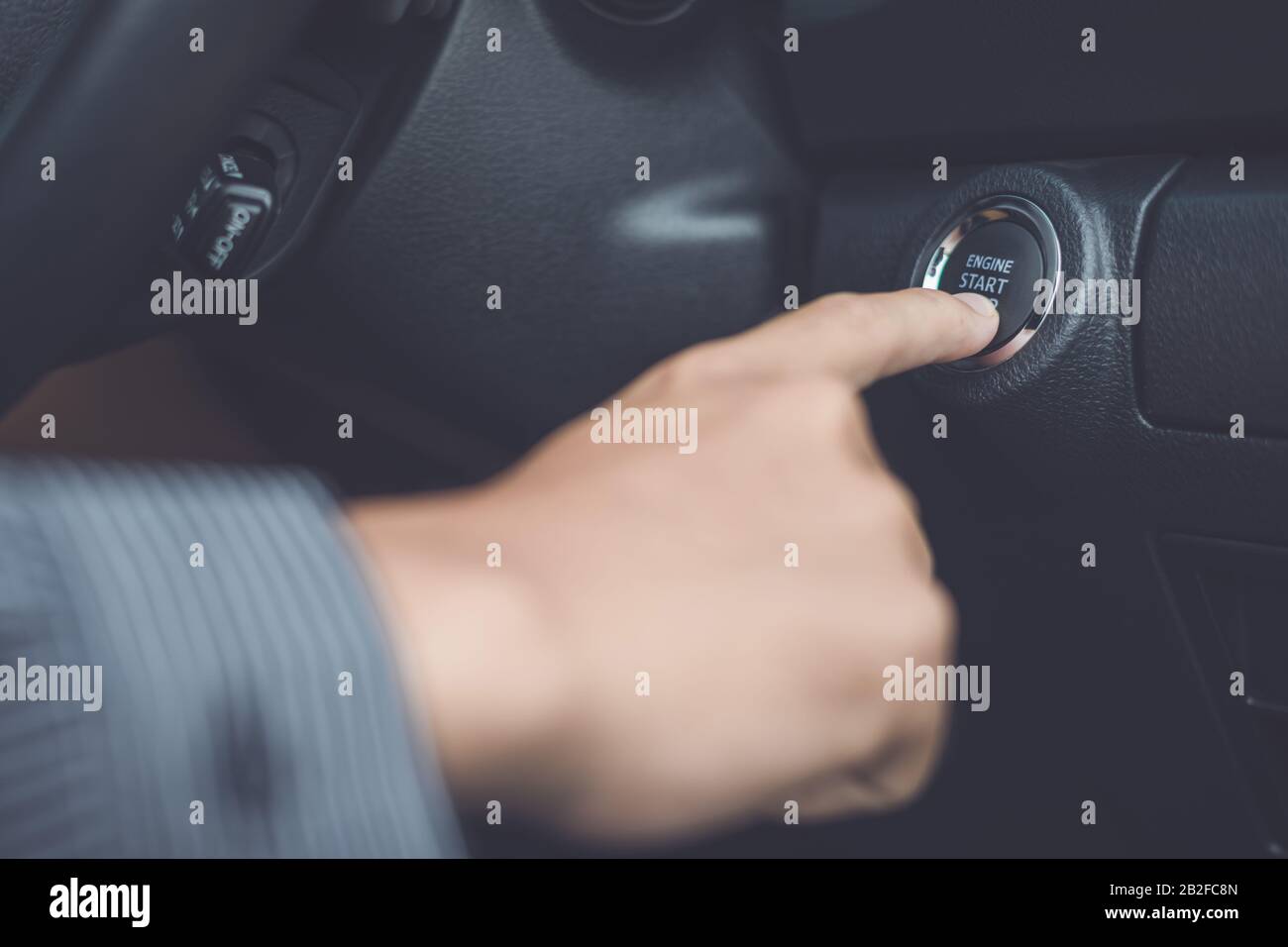 Mano di uomo premere il pulsante START/STOP motore auto all'interno della vettura moderna. Concetto di trasporto Foto Stock