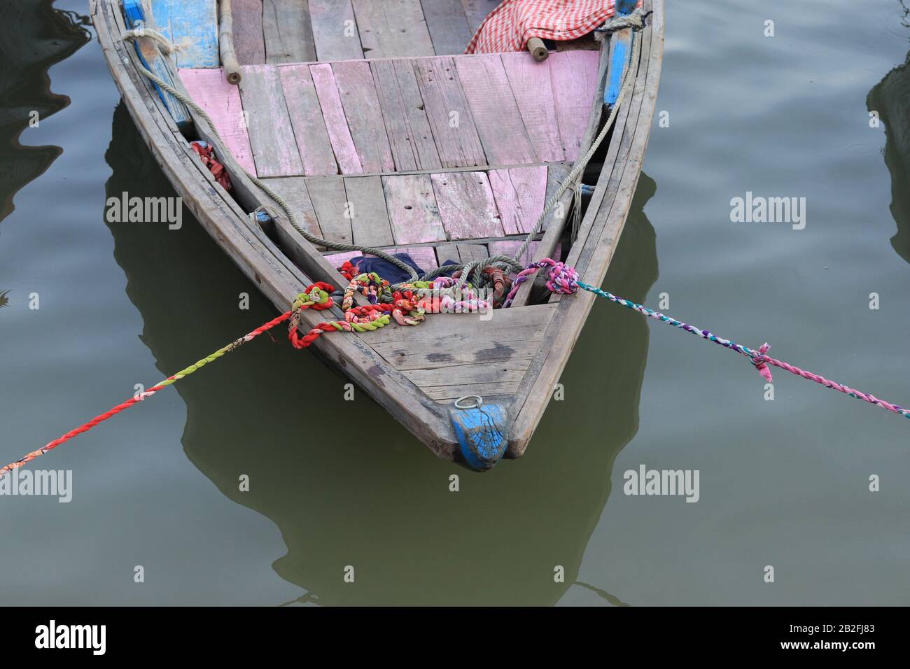 Tradizionale barca indiana legata con corde alla riva del fiume Ganga Foto Stock