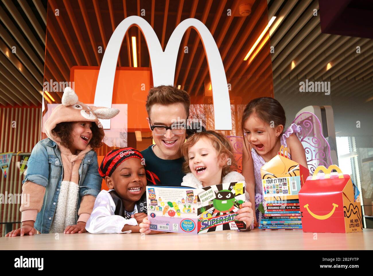 L'autore e musicista per bambini Tom Fletcher legge (da sinistra a destra) ai quattro anni Pearl Prasad, Zane-Ellis Yeboah, Maisie Patey e Alexandra Ancharaz, come viene presentato come nuovo McDonald's Happy Readers Ambassador per celebrare la Giornata Mondiale del Libro, Londra. Foto PA. Data di emissione: Martedì 3 marzo 2020. Dall'inizio di febbraio, la scatola dei pasti felici nel Regno Unito e in Irlanda ha incluso un gettone del libro libero dalla Giornata del libro del mondo, che dà a milioni di famiglie l'accesso ad uno dei 12 libri liberi dai librai attraverso il programma dei lettori felici. Foto cre Foto Stock