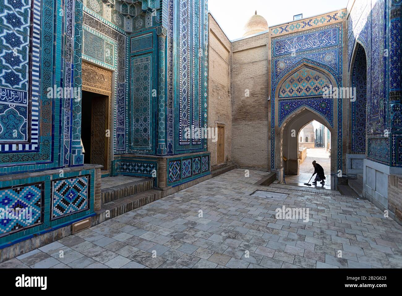 Donna che spazzava con una scopa il pavimento a Shah-i-Zinda in Samarcanda, Uzbekistan Foto Stock
