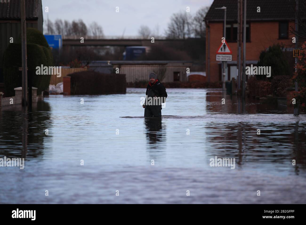 A Snaith, nello Yorshire, un uomo si infila per le acque alluvionali, in totale 82 moniti sono ancora in vigore per l'Inghilterra, il Galles e la Scozia dopo gli effetti di Storm Jorge durante il fine settimana. Foto Stock