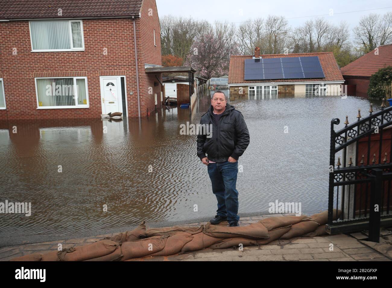 Kevin Lorryman, al di fuori del suo bungalow a Snaith, Yorshire, che è circondato da acqua come un totale di 82 avvertimenti alluvione sono ancora in vigore per l'Inghilterra, il Galles e la Scozia dopo gli effetti di Storm Jorge durante il fine settimana. Foto Stock