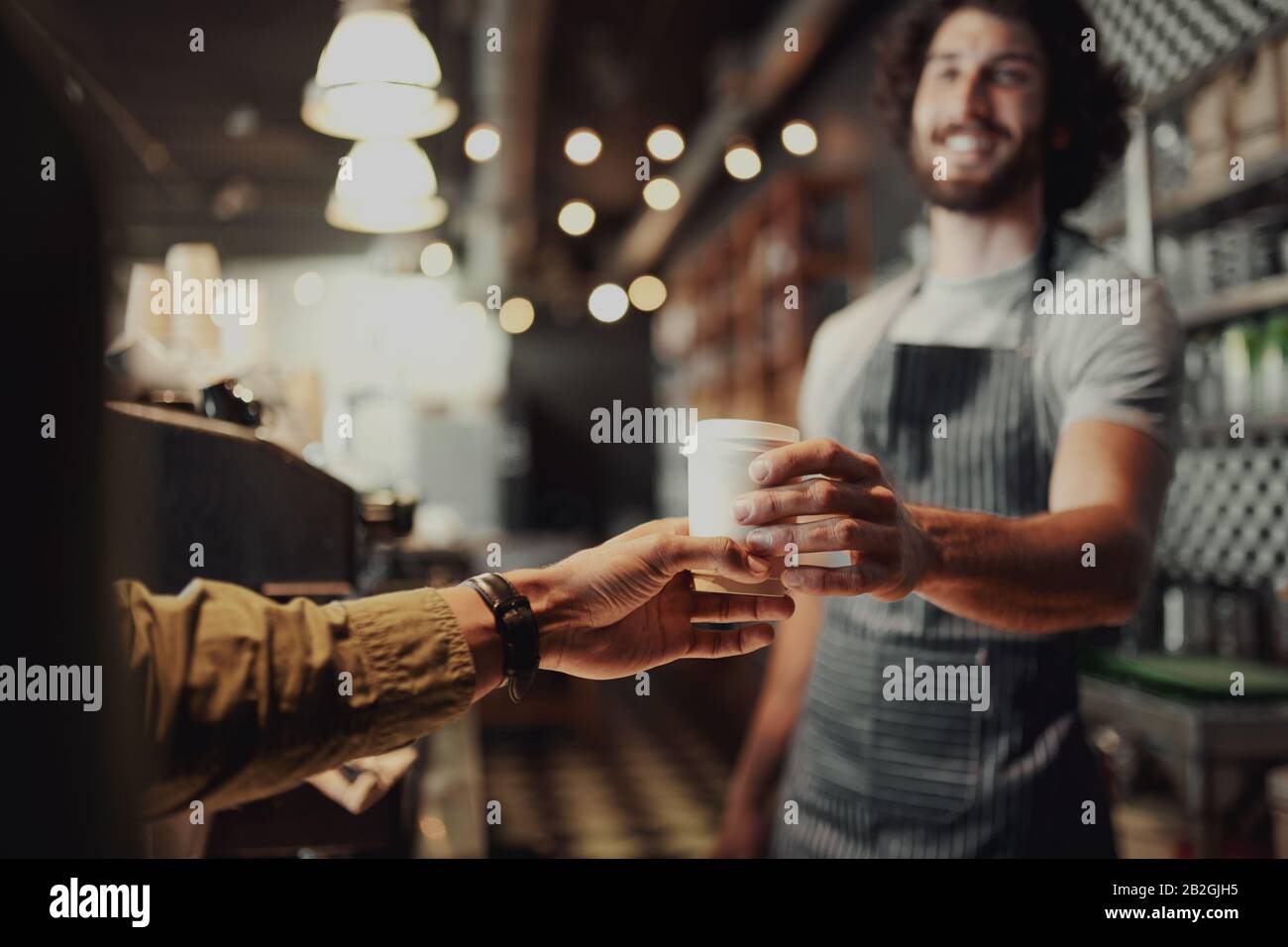 C'era un cameriere che serviva una tazza di caffè freddo al banco del bar Foto Stock