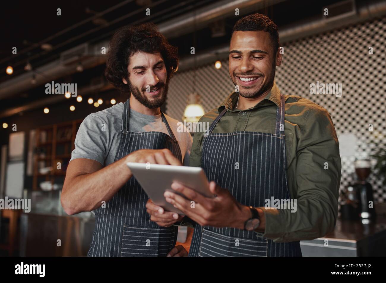 I collaboratori di caffè multietnici che lavorano insieme in un bar utilizzando un tablet digitale Foto Stock