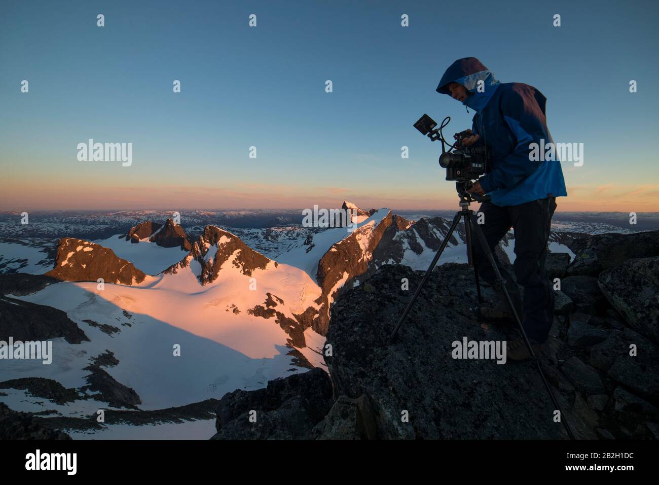 L'uomo filma in cima al mondo, in cima, guardando in montagna Foto Stock
