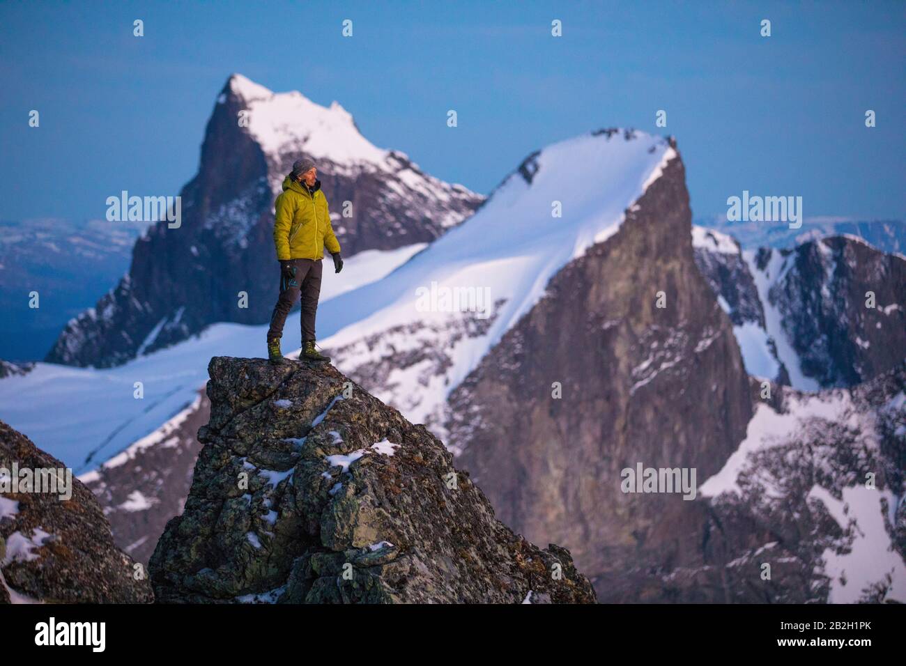 Uomo che si trova in cima al mondo, sulla cima, guardando le montagne Foto Stock