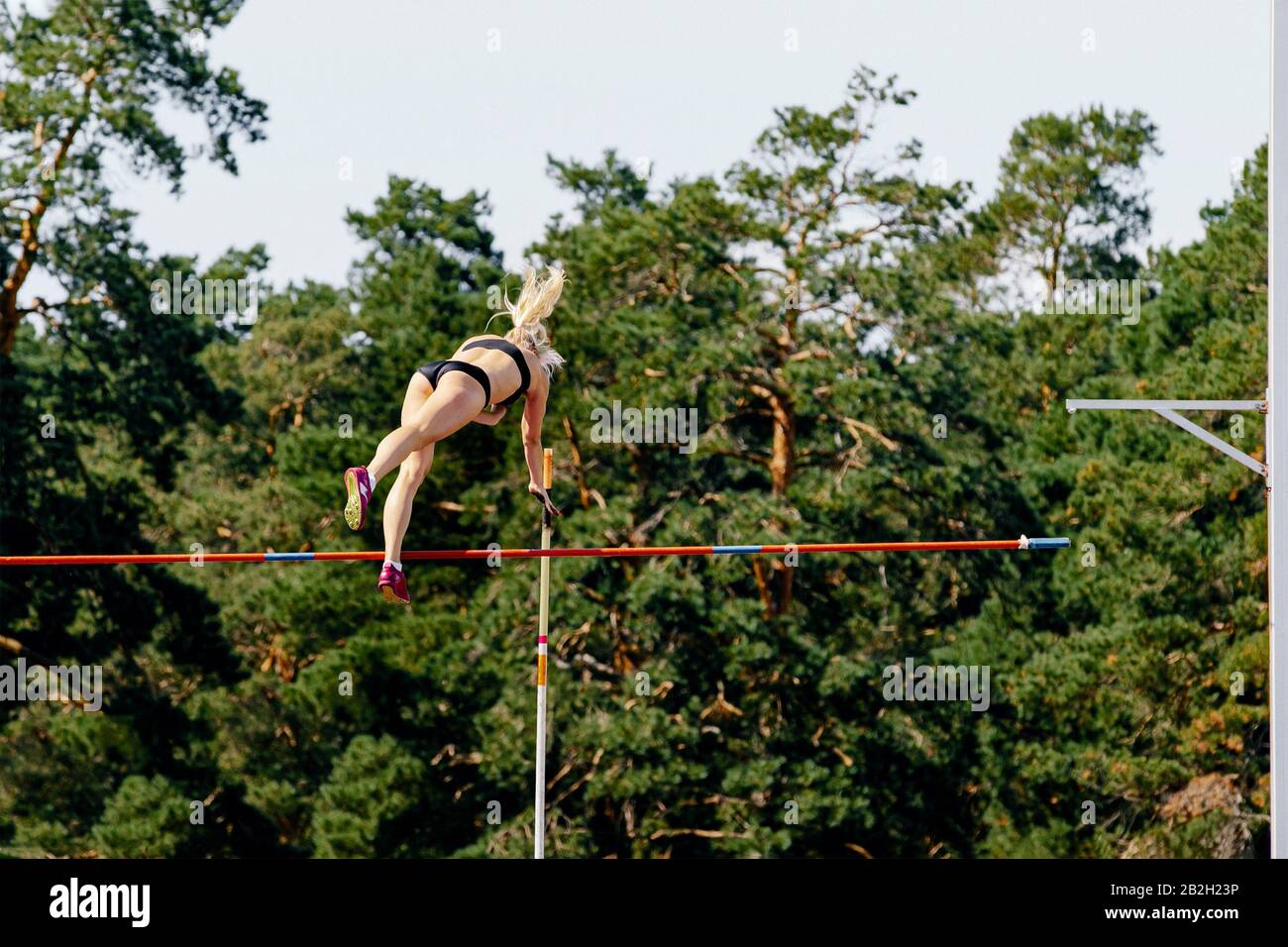 pole vault donna atleta salto sullo sfondo della foresta Foto Stock