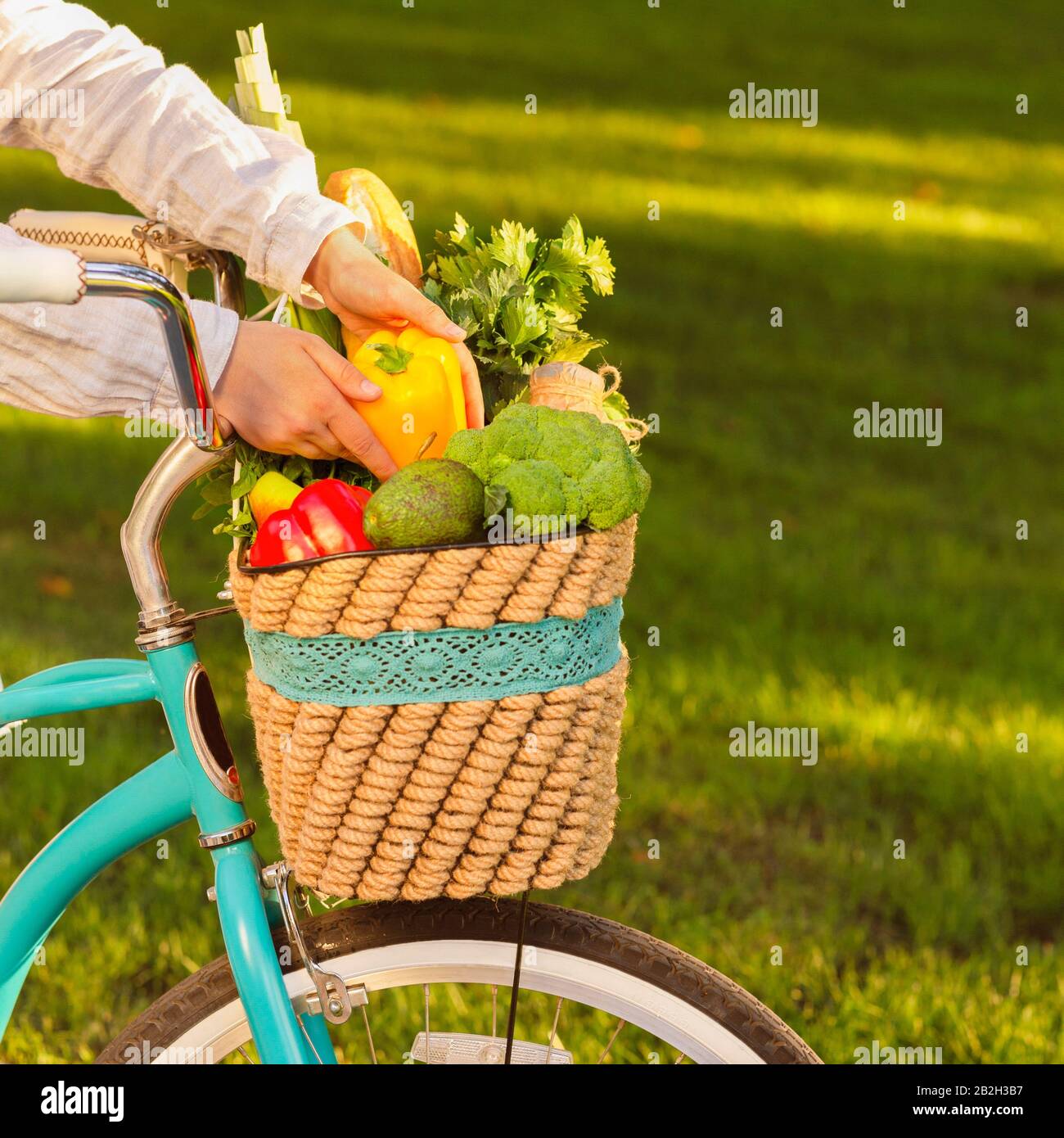 Donna vuole mangiare paprica fresca dal cesto pieno di verdure organiche Foto Stock