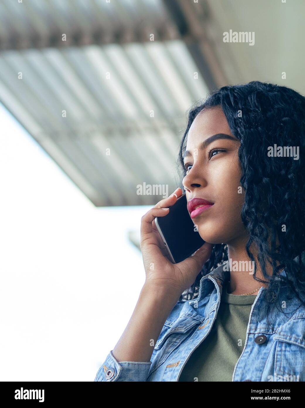 Una donna latina concentrata con capelli ricci che ha una chiamata telefonica Foto Stock