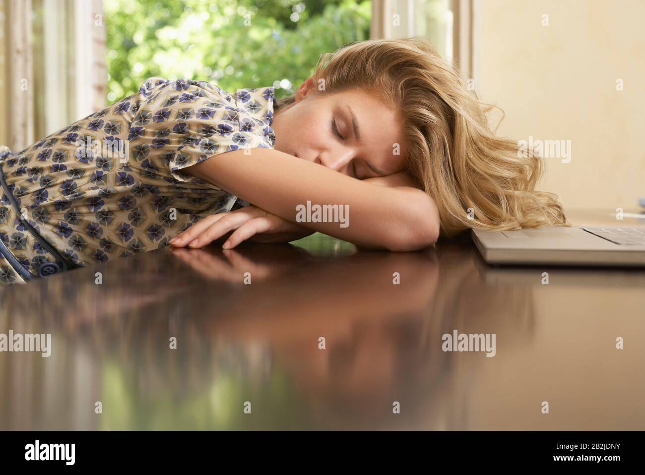 Giovane donna che dorme davanti al computer portatile nel soggiorno Foto Stock