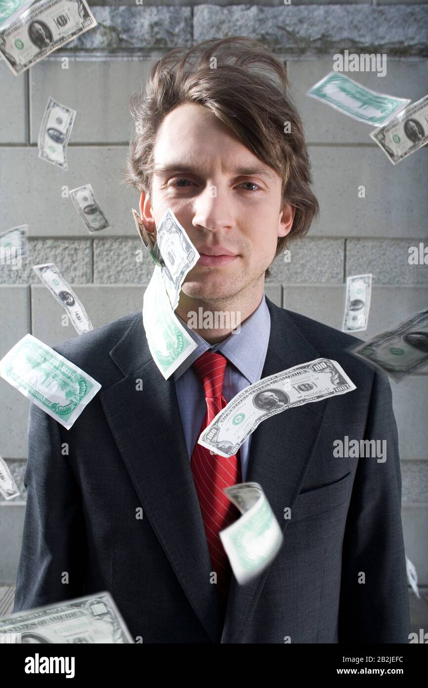 Busines uomo circondato da caduta di denaro all'aperto ritratto Foto Stock