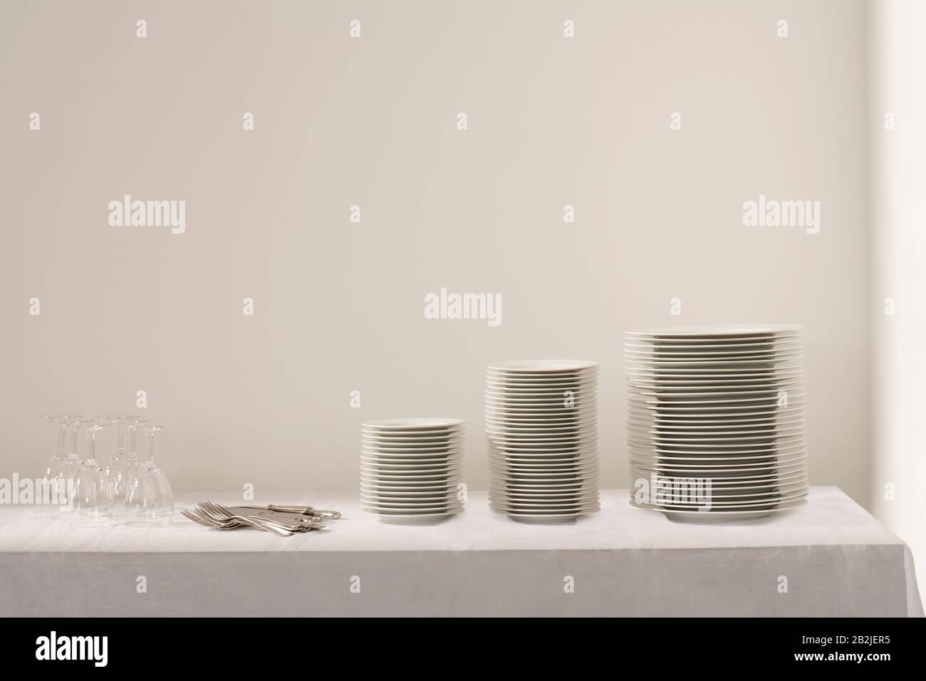 Pile di piatti posate e wineglasses sul tavolo Foto Stock
