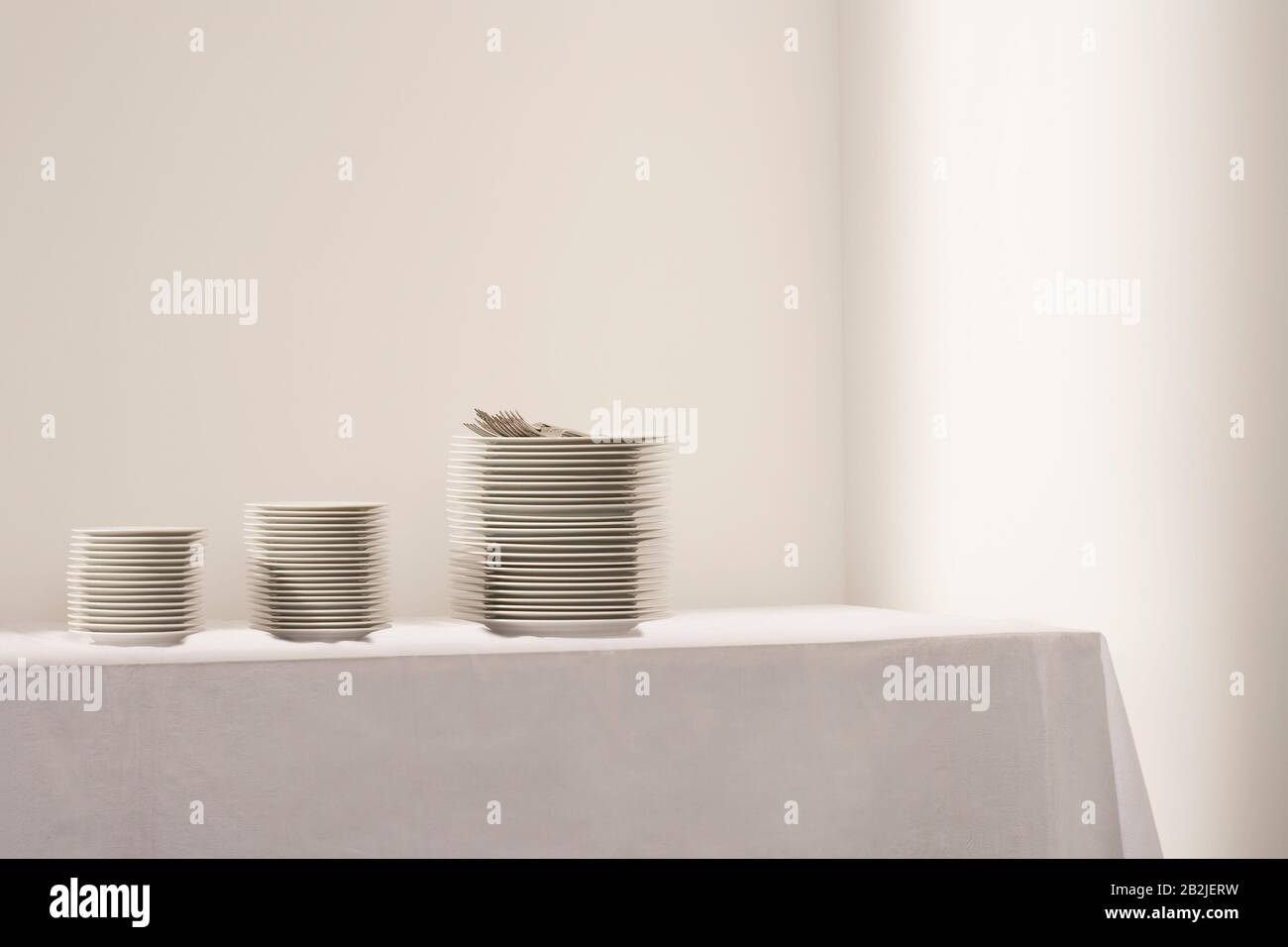 Tre pile di piatti e posate sul tavolo Foto Stock