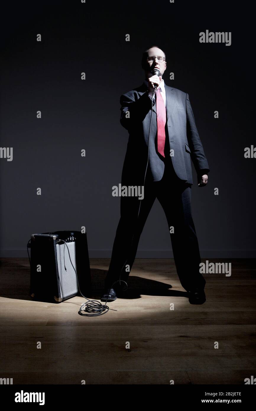 Uomo in abito pieno che canta nel microfono Foto Stock