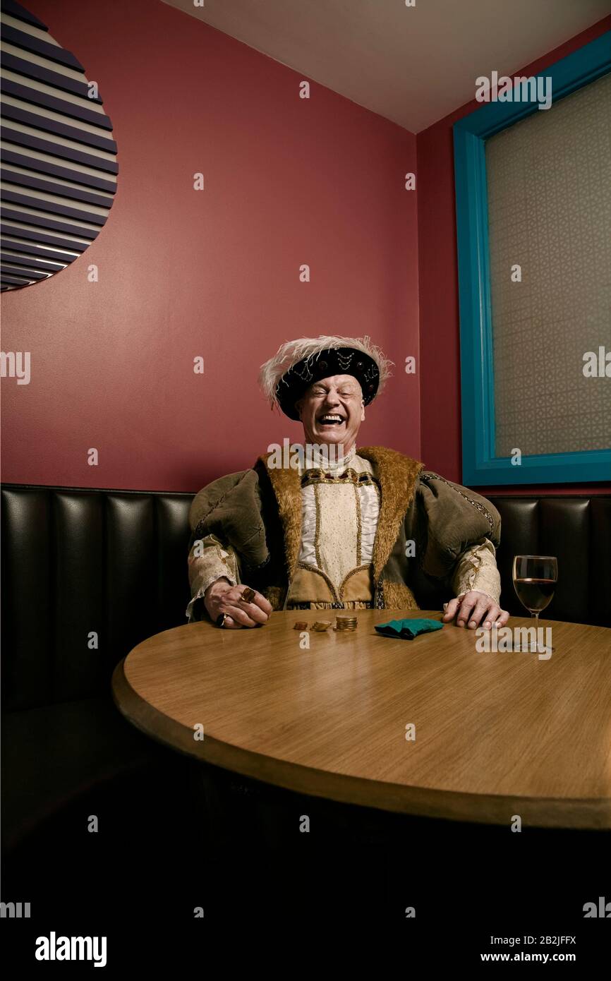 Re Enrico VIII contando i soldi a tavola ridendo Foto Stock