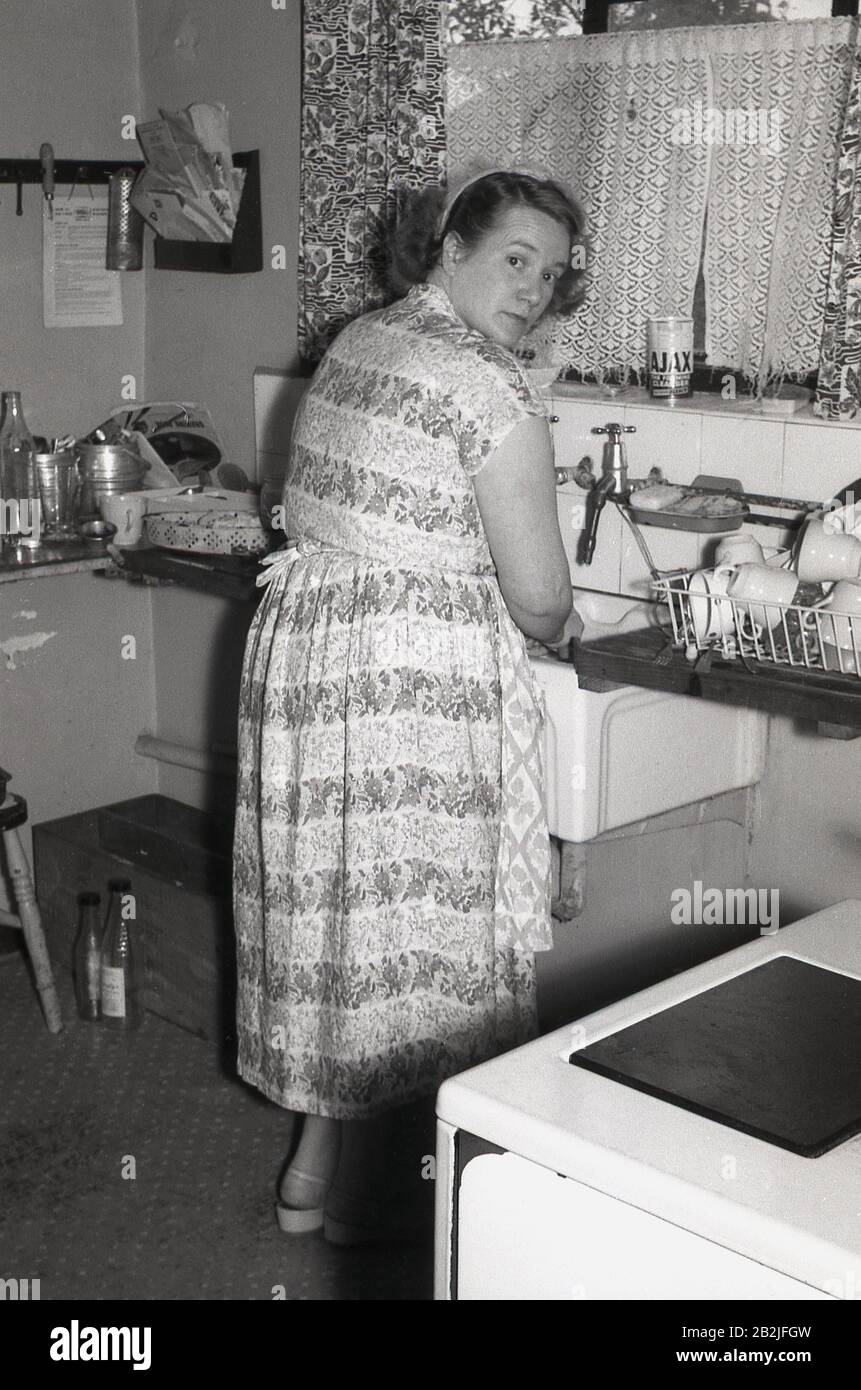 Anni '1950, storica, una signora che lava i piatti nel lavandino della sua cucina, Inghilterra, Regno Unito. Foto Stock