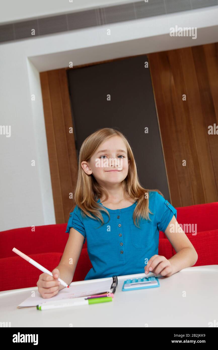 Ritratto di una ragazza felice che fa i compiti a tavola Foto Stock