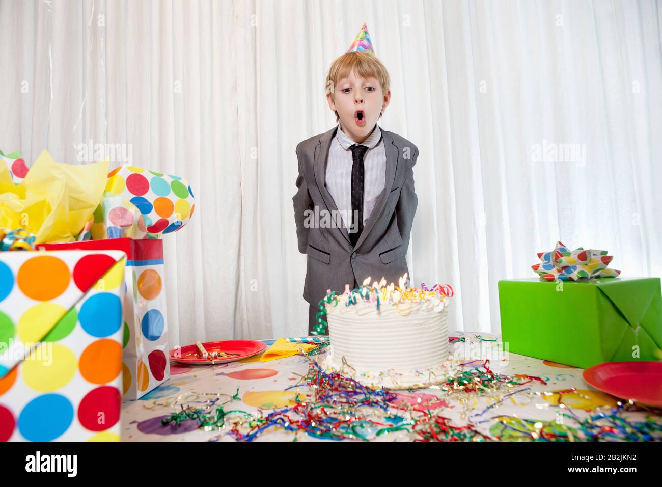 Pre-teen compleanno ragazzo che soffia candele sulla torta Foto Stock
