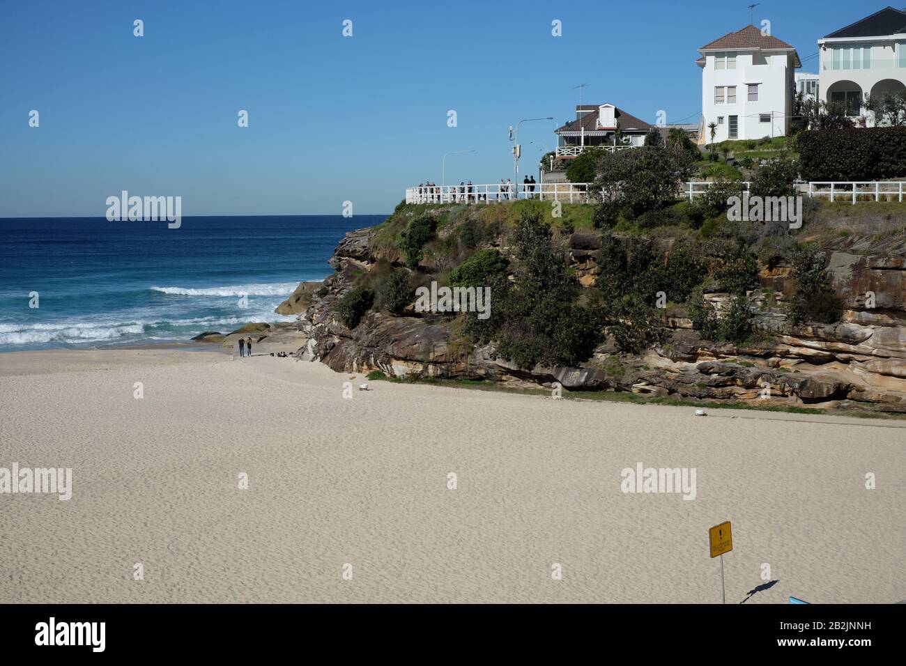 Spiaggia di Tamarama in una perfetta giornata di sole, sabbia, impronte, il blu dell'oceano e un cielo blu chiaro, case sulla spiaggia, un paesaggio di Sydney Foto Stock