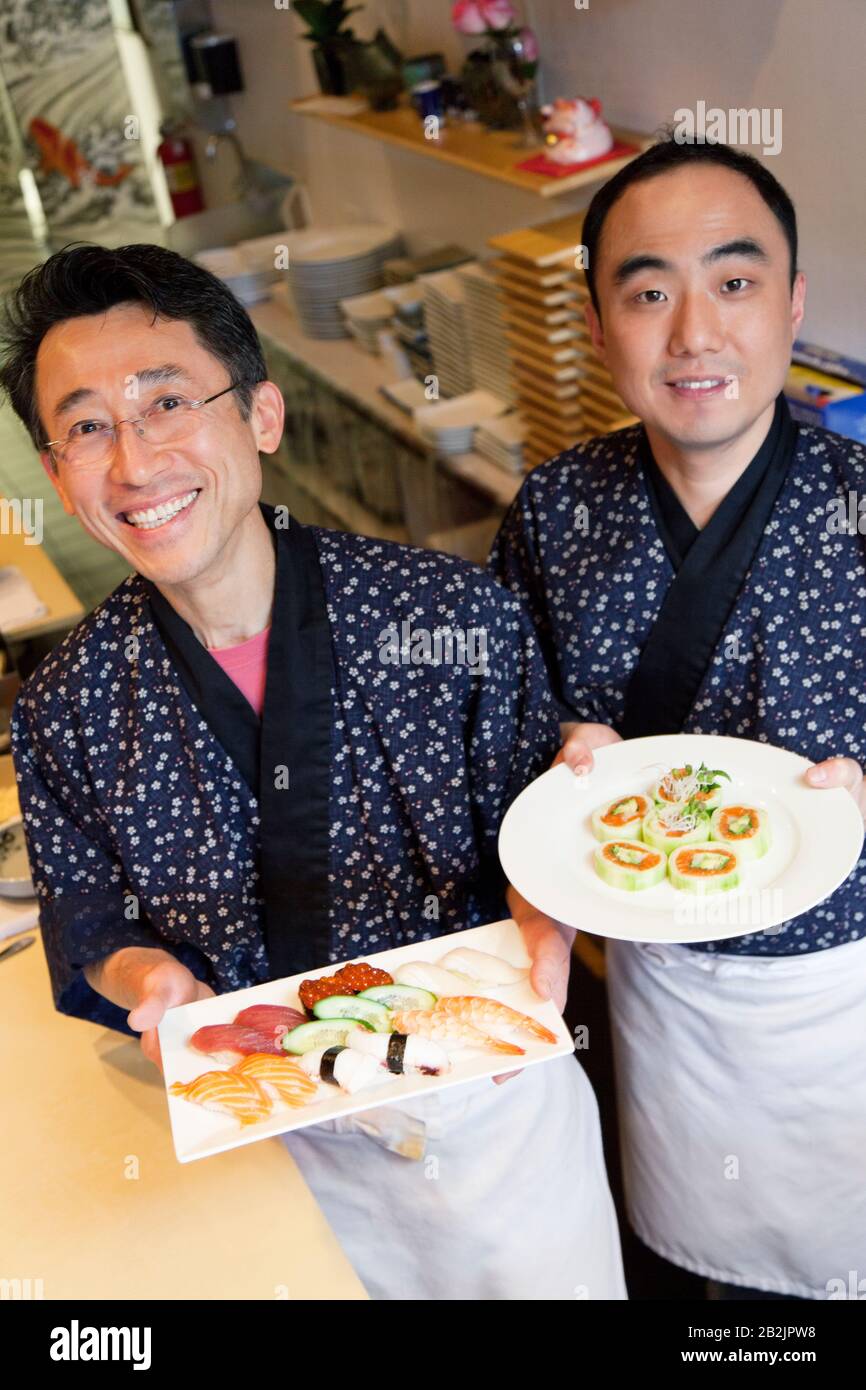 Chef asiatici felici con cucina giapponese nel ristorante Foto Stock