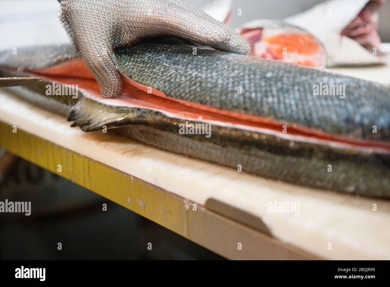 Primo piano della mano dell'uomo con l'affettare il pesce di salmone Foto Stock