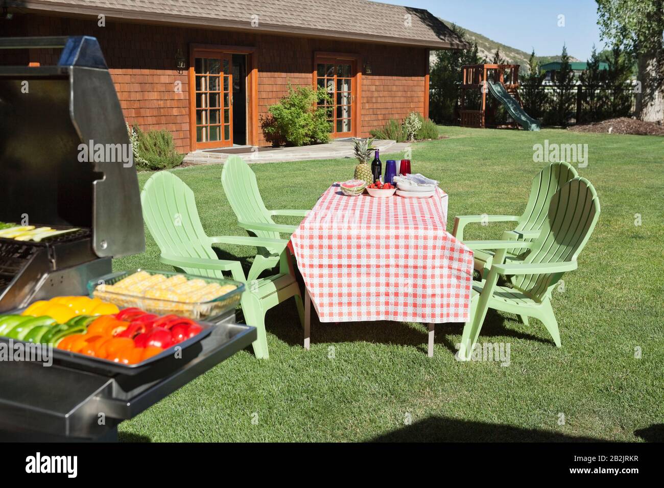 Tavolo da pranzo e sedie con barbecue grill sul prato di fronte alla casa di campagna Foto Stock