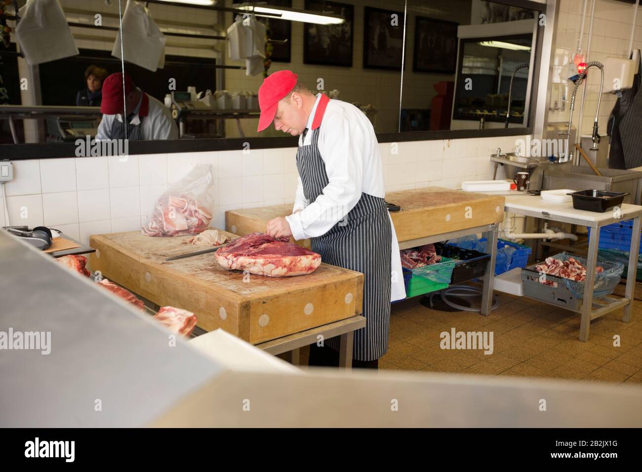 Uomo maturo taglio beefsteak in macellaio negozio Foto Stock