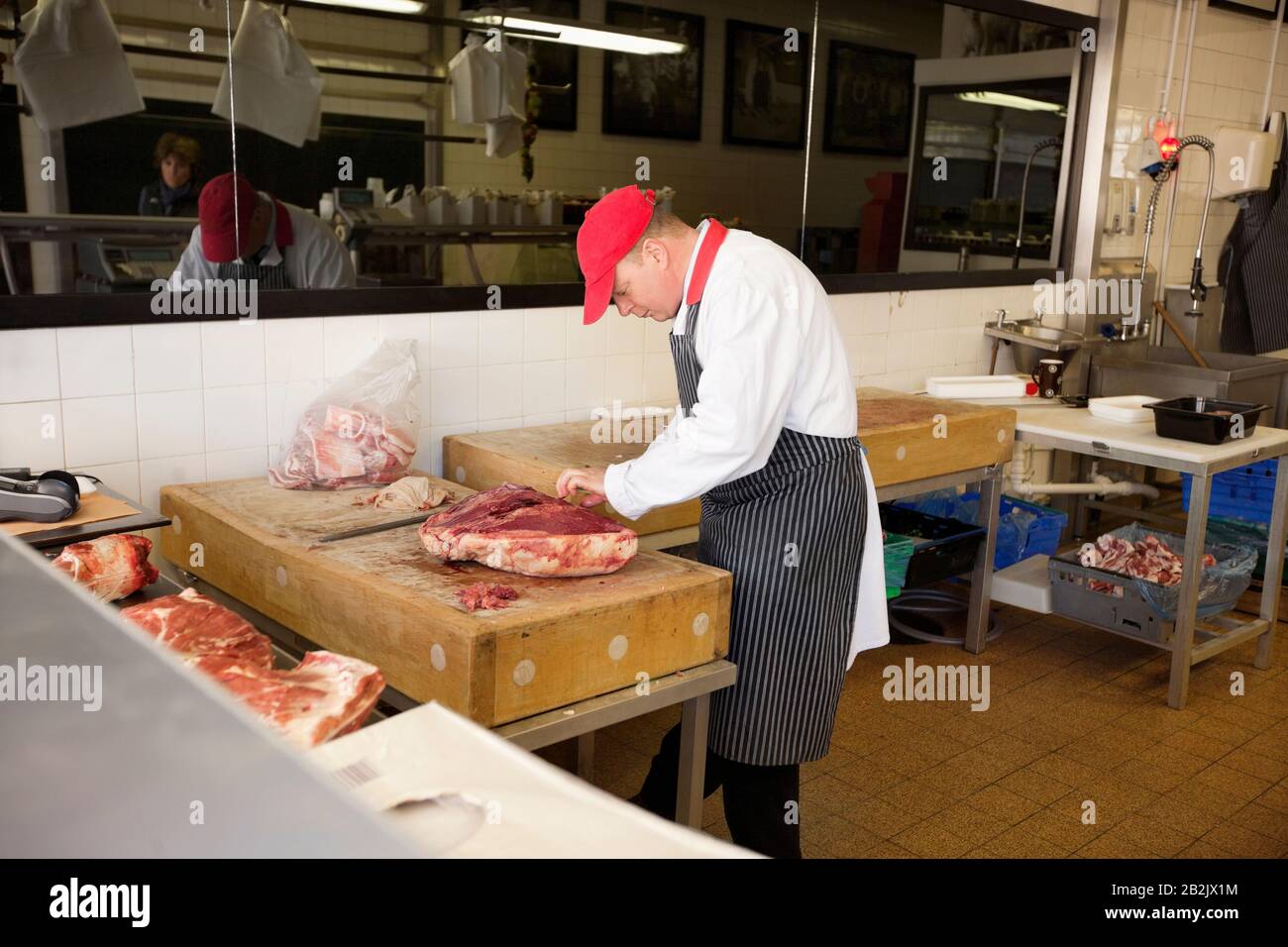 Macellaio maschio affettare beefsteak in negozio Foto Stock