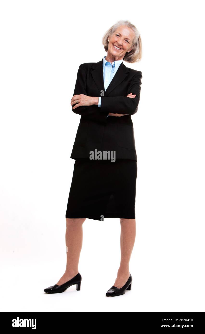Ritratto di donna d'affari anziana in piedi con le braccia incrociate contro sfondo bianco studio Foto Stock