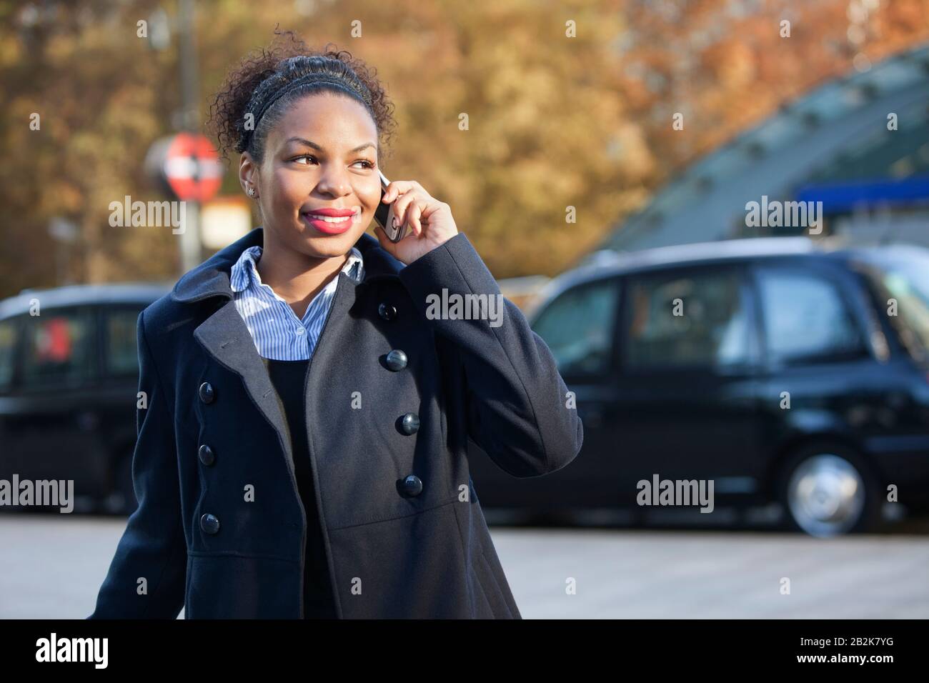 Giovane donna afroamericana sorridente che usa il cellulare all'aperto Foto Stock