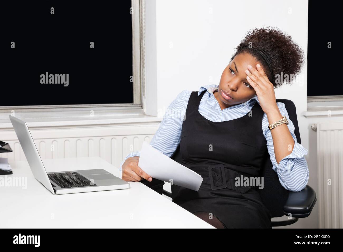Giovane donna d'affari stanco di fronte al laptop alla scrivania in ufficio Foto Stock