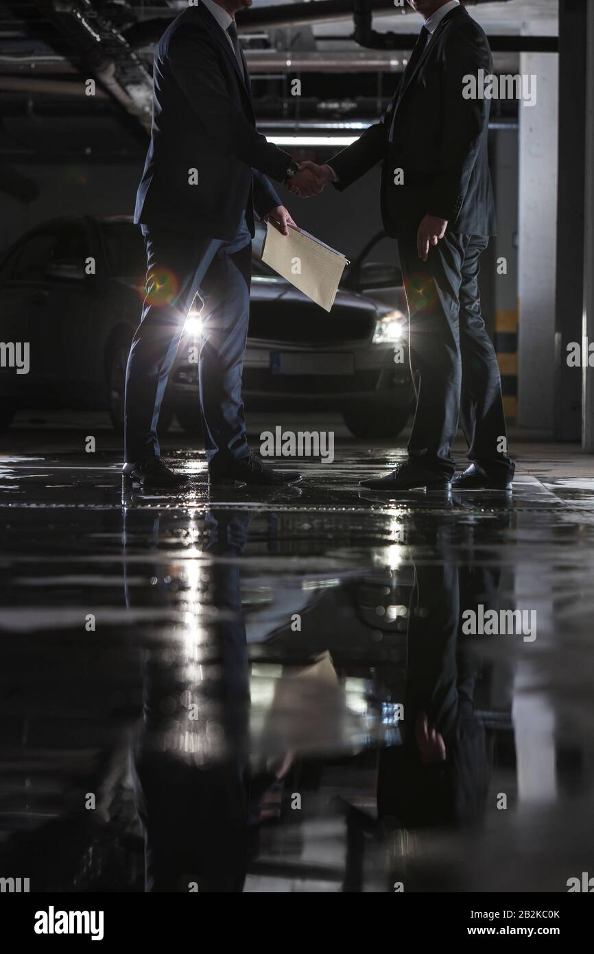 Sezione bassa di uomini d'affari che conducono affari sospetti nel parcheggio Foto Stock