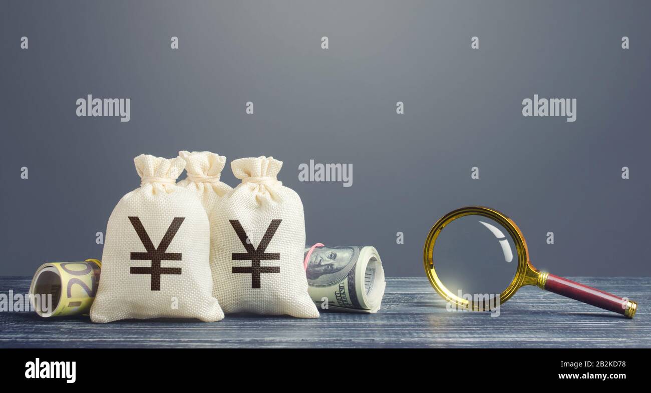 Yen yuan borse di denaro e lente di ingrandimento. Monitoraggio finanziario delle transazioni in contanti sospette. Ricerca di fonti di finanziamento dei progetti. Redditizio i Foto Stock